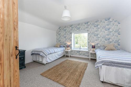 a bedroom with two beds and a window at Spence Cottage, Birdham in Birdham