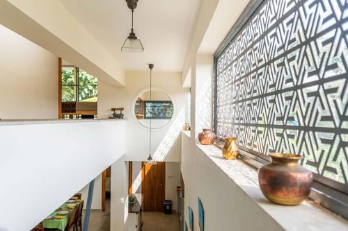 a hallway with a large window and a large vase on a counter at Davey's Townhouse by VEO - Part of StayVista in Mysore
