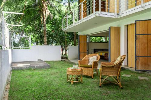 a patio with chairs and a table in the grass at Davey's Townhouse by VEO - Part of StayVista in Mysore