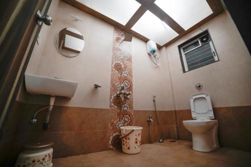 a bathroom with a toilet and a sink and a mirror at Highgarden Villa in Mahabaleshwar