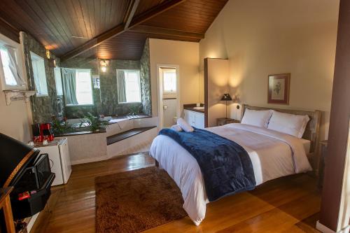 a bedroom with a large bed in a room with windows at Villa Don in Petrópolis