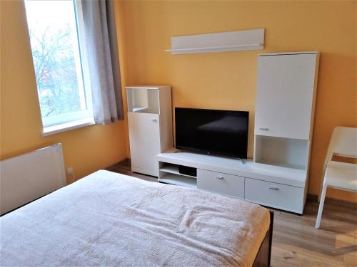 Schlafzimmer mit einem Bett und einem Schrank mit einem TV in der Unterkunft Studio Daola in Danzig