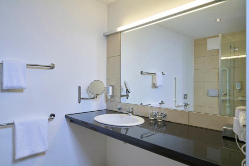a bathroom with a sink and a large mirror at Fairmotel Dornbirn in Dornbirn