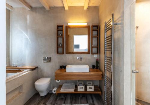 a bathroom with a sink and a toilet and a mirror at O Lofos Luxury Boutique Suites in Agios Stefanos