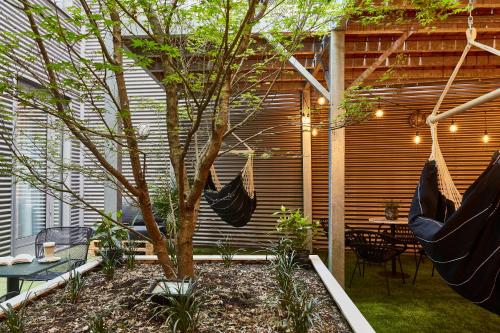 a patio with a tree with hammocks and a table and chairs at Hotel Indigo Antwerp City Centre by IHG in Antwerp