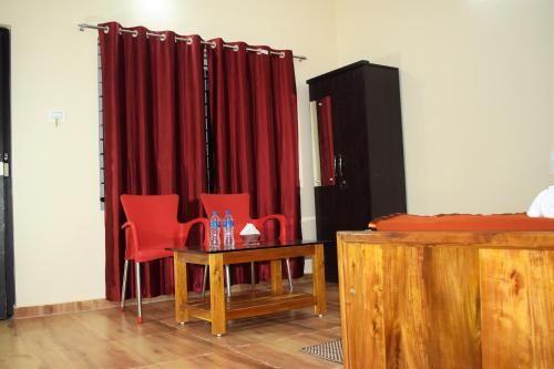 a room with red curtains and a table and chairs at Viraz Valley in Gokarna