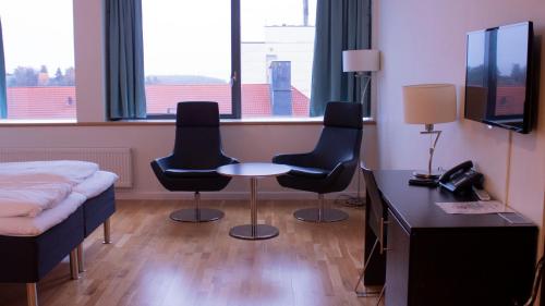 Habitación con 2 sillas, mesa y cama en Hotel Montebello, en Oslo