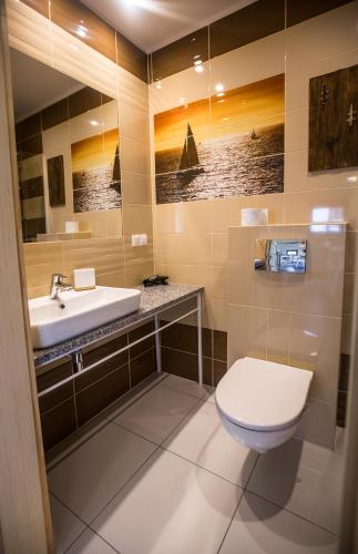 a bathroom with a sink and a toilet and a mirror at Balfala - komfortowe parterowe domki nad morzem z klimatyzacją in Ostrowo