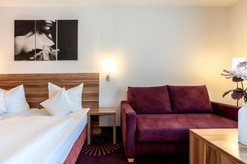 une chambre d'hôtel avec un lit et un canapé dans l'établissement Altstadthotel Guesthouse Die Galerie, à Ingolstadt