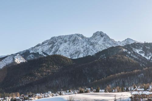 a snow covered mountain with a town in the foreground at TatryTop Panorama Lux Spa in Kościelisko