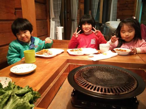 three children sitting at a table eating food at ログハウスkizuki in Tsuru 