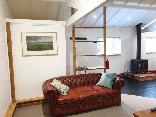 a living room with a brown leather couch at Church Farm Lodge in Southburgh