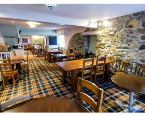 un restaurante con mesas y sillas y una pared de piedra en Crown Hotel, en Pwllheli