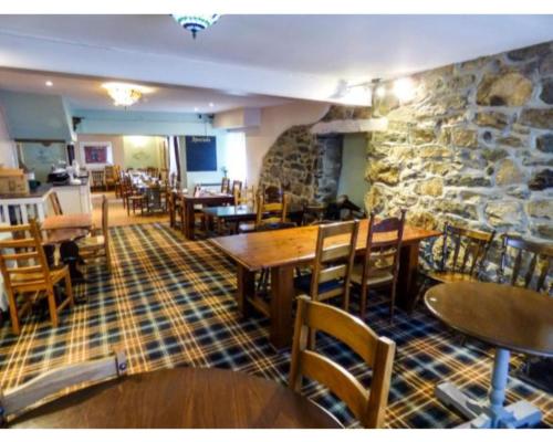 a restaurant with tables and chairs and a stone wall at Crown Hotel in Pwllheli