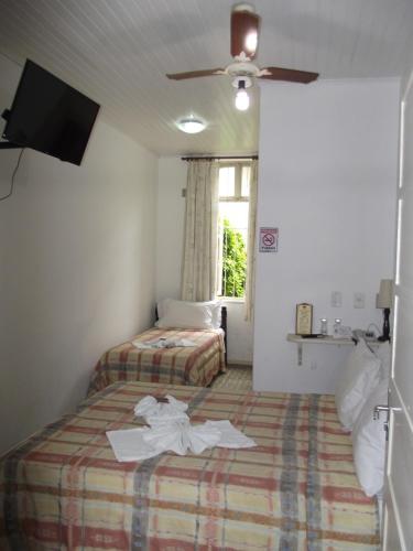 a hotel room with two beds and a flat screen tv at Pousada Max Pomerode in Pomerode