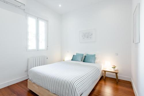 een witte slaapkamer met een groot bed met blauwe kussens bij Luxury Apartment Princesa in Madrid