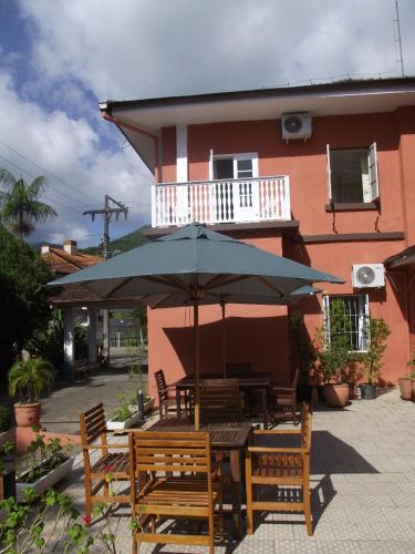 a table with an umbrella in front of a building at Pousada Max Pomerode in Pomerode