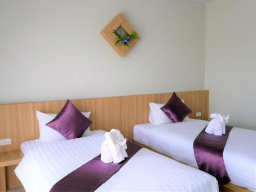 three beds in a room with purple and white sheets at The Beach at Klong Muang in Klong Muang Beach