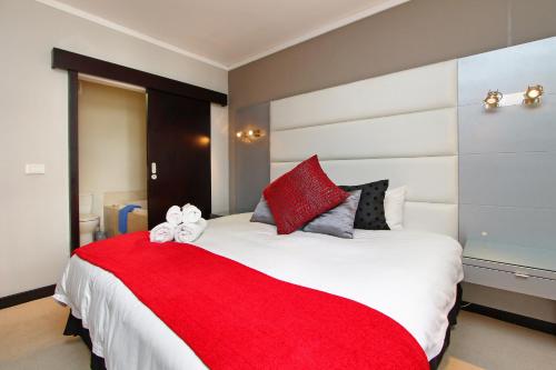 a bedroom with a large bed with a red blanket at Full Power, long stay rates, walk to V&A Waterfront, fibre WIFI, gym & pool in Cape Town