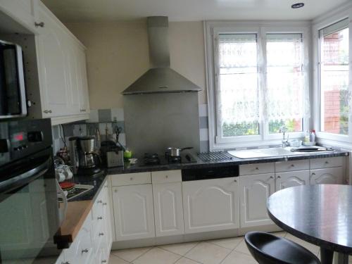 - une cuisine avec des placards blancs, un évier et une table dans l'établissement Chambre Coquette, à Aulnay-sous-Bois