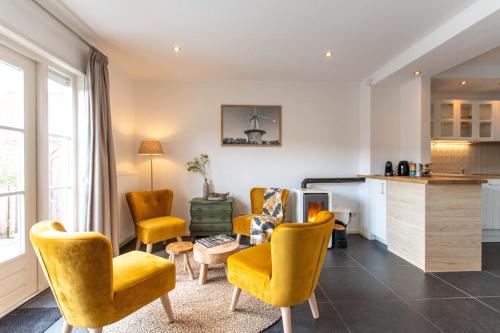 a living room with yellow chairs and a kitchen at Vakantiewoning t Uusje Wemeldinge in Wemeldinge