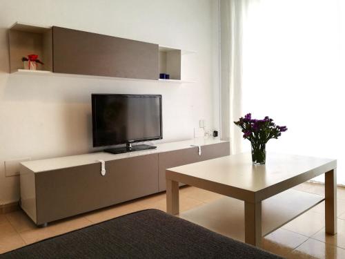 - un salon avec une télévision et une table dans l'établissement First Line Beach Apartment with Two Bedrooms and Sea View, à Nerja
