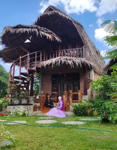 a group of people sitting in front of a house at Green Travelodge Bukit Lawang in Bukit Lawang