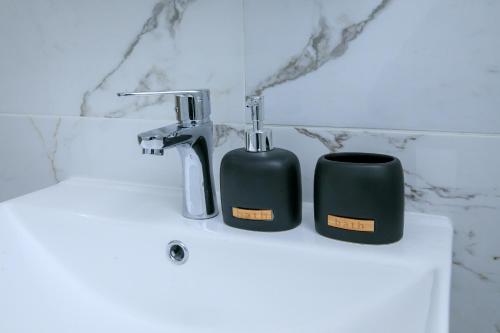 two black mugs sitting on top of a sink at ГеВе Апартаменти in Sandanski