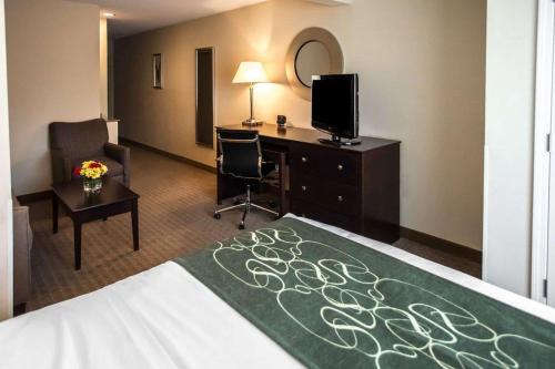 a hotel room with a bed and a desk and a television at Comfort Suites University Area Notre Dame-South Bend in South Bend