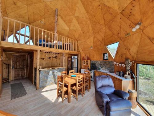 eine Küche und ein Esszimmer einer Hütte mit Holzdecke in der Unterkunft Domos Curiñanco vista al mar in Valdivia