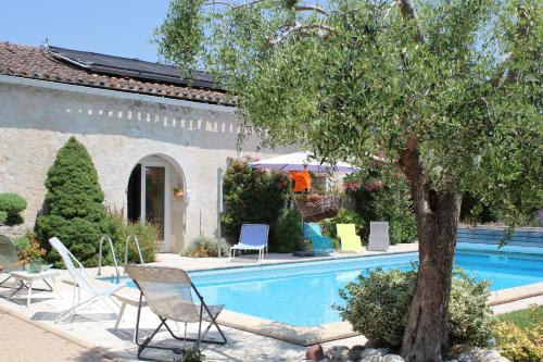 a swimming pool with chairs and a tree next to a house at Les charmes de Vincent - le loft Cabernet in Fronsac