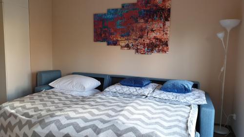 a bed with two pillows and a painting on the wall at LAGUNA Apartament 23 Willa Leśna in Polanica-Zdrój