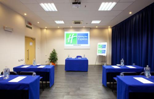 a conference room with blue tables and a screen at Holiday Inn Express Reggio Emilia by IHG in Reggio Emilia