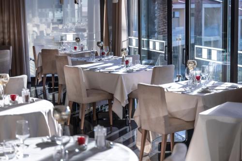 a restaurant with white tables and chairs and windows at Park Hotel Imperial in Limone sul Garda