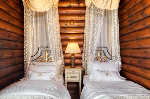 two beds in a room with wooden walls at All Seasons Paradise in Khrisovítsion