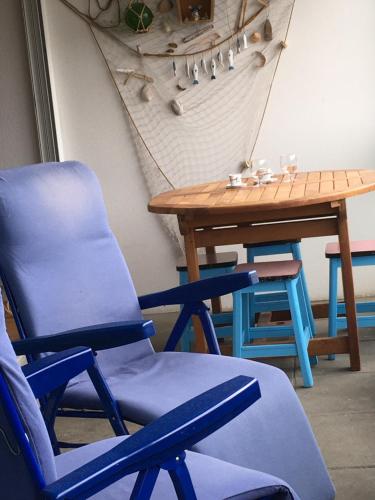 une chaise bleue, une table, une table et des chaises dans l'établissement Appart du bord de Mer, à Audierne