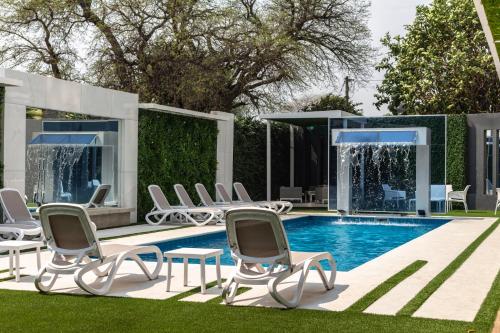 a pool with chaise lounge chairs and a house at Hotel Los Alpes Cipreses in Asunción