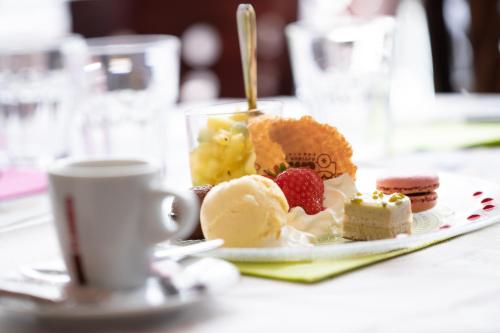 a plate of desserts on a table with a cup of coffee at Hotel-Restaurant Espace Squash 3000 in Mulhouse