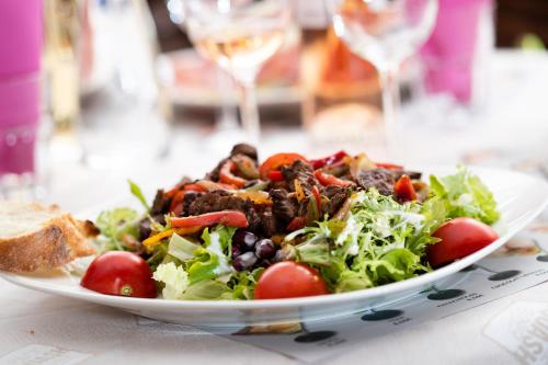 a plate of salad on a table with wine glasses at Hotel-Restaurant Espace Squash 3000 in Mulhouse