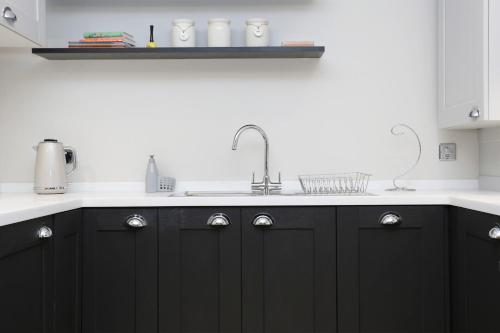 a kitchen with black cabinets and a sink at ALTIDO Newly Refurbished Apartment on the Historic Royal Mile in Edinburgh