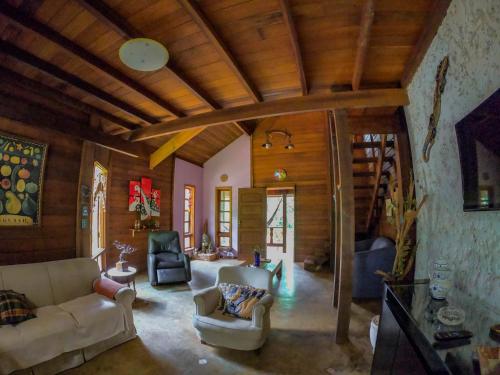 a living room with couches and chairs and wooden ceilings at Chalé Cores da Mata in Brumadinho