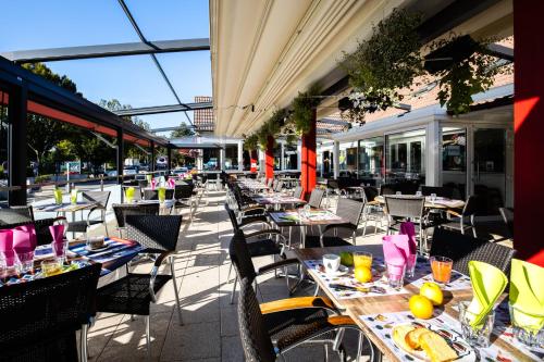 - une rangée de tables et de chaises sur la terrasse dans l'établissement Hotel-Restaurant Espace Squash 3000, à Mulhouse