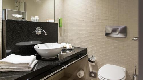 a bathroom with a sink and a toilet at Mövenpick Hotel Lausanne in Lausanne