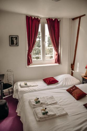 deux lits dans une chambre avec des rideaux rouges dans l'établissement B&B Château De La Houssoye, à La Houssoye