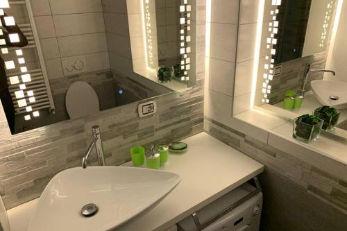 W łazience znajduje się biała umywalka i 2 lustra. w obiekcie Stefano Rho Apartment Near RHO-FIERA and MILANO w mieście Rho
