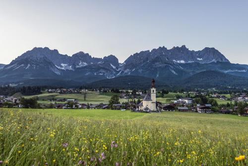 a small town with a church in a field with mountains at KaiserMoments in Going