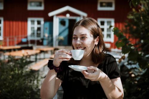 a woman is drinking a cup of coffee at Våffelcafé Bed & Breakfast in Dannäs