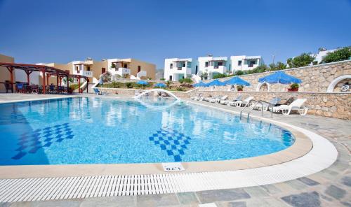 uma piscina num resort com cadeiras e guarda-sóis em Golden Sun Apartments em Arkasa