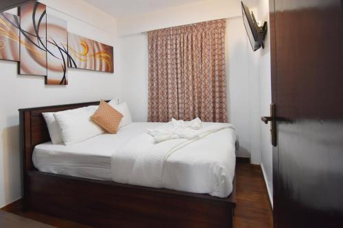 ヌワラエリヤにあるVista Apartment Mariners Cabinのベッドルーム1室(白いシーツ付きのベッド1台、窓付)