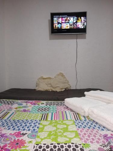a room with a bed with a tv on the wall at Departamentos Pachamama in Tunuyán